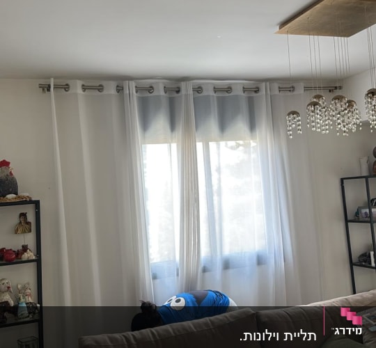 אדם עובד ליד חלון בסלון עם וילונות